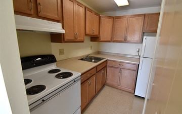 Dover apartment for rent - A kitchen with brown cabinets and white appliances.