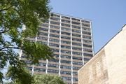 Chicago apartment for rent - A tall building with many windows is seen behind a tree.