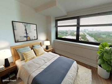 Chicago apartment for rent - A bedroom with a large bed and a window overlooking a cityscape.