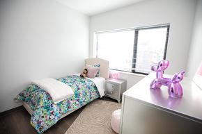 Chicago apartment for rent - A bedroom with a floral bedspread and a pink unicorn figurine on the desk.