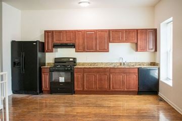Chicago apartment for rent - A kitchen with wooden cabinets and a black refrigerator.
