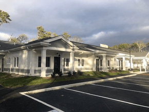 Brewster apartment for rent - A white building with a black door and windows is surrounded by a parking lot.