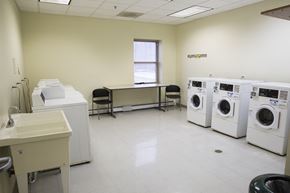 Chicago apartment for rent - a washer and dryer room with a row of washing machines and a table