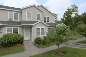 East Sandwich townhouse for rent - A house with a grey roof and white walls with a small tree in front of it.