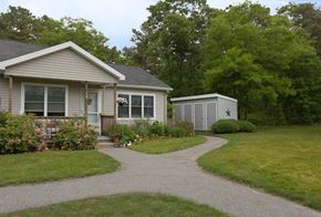 East Sandwich townhouse for rent - A house with a grey roof and a small shed in the backyard.