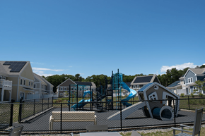 Sandwich apartment for rent - a playground with slides and other equipment in front of a row of houses