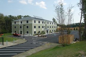 Weymouth apartment for rent - a building with solar panels on the roof and a parking lot