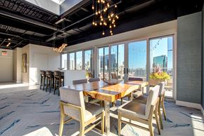 Chicago apartment for rent - a dining room with a long wooden table and chairs and a view of the city