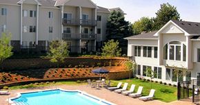 Omaha apartment for rent - Swimming pool with sundeck and poolside lounge chairs, beautiful landscaping, lush landscaping, apartments with pool view, and park-like setting at Kensington Woods Apartments in Omaha, Nebraska