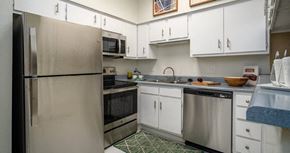 Houston apartment for rent - Kitchen with white cabinets, stainless steel appliances, and breakfast bar at Woodlake on the Bayou Apartments
