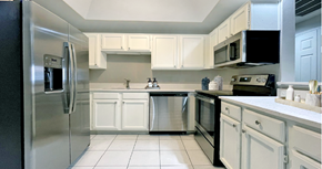 Dallas apartment for rent - Spacious bright white kitchen with white cabinets, stainless steel appliances, side-by-side refrigerator, and tiled floor at Prestonbridge Apartments in North Dallas