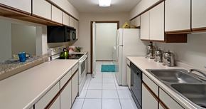 Omaha apartment for rent - Kitchen with abundant countertop space and cabinets, granite breakfast bar, glass top stove, and separate laundry room at LionsHead Apartments in Omaha Nebraska
