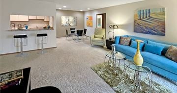 Omaha apartment for rent - A living room with a blue couch and a glass table.