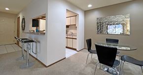 Omaha apartment for rent - Dining room area with painted feature wall, granite breakfast bar, and kitchen with tiled floor at LionsHead Apartments in Omaha Nebraska