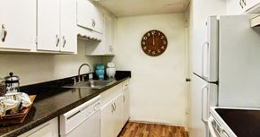 Houston apartment for rent - Apartments near the Galleria with bright white kitchens, black countertops, and wood plank flooring at Plantation apartments in Houston.