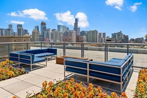 Chicago apartment for rent - the chicago skyline of the city from a rooftop patio with blue couches