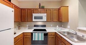 Houston apartment for rent - Spacious kitchen with honey brown toned cabinets, u-shaped kitchen, tile floors, and lots of counter space at Tuscany Park Apartments in Houston