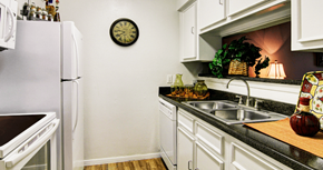 Houston apartment for rent - Bright white kitchens with black countertops and wood plank floors at Waters of Winrock Apartments in Houston