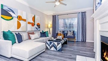 Dallas apartment for rent - A living room with a white couch, a fireplace, and a painting on the wall.