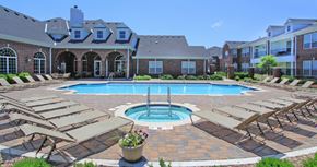 Lincoln apartment for rent - Luxury apartments with red brick exteriors, swimming pool, pool-side lounge chairs, beautiful landscaping, and scenic views at Rockledge Oaks Apartments in Lincoln, Nebraska