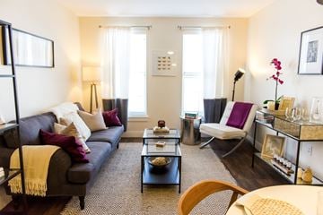 Wyandanch apartment for rent - A living room with a grey couch, a coffee table, a chair, and a table with a vase of flowers.