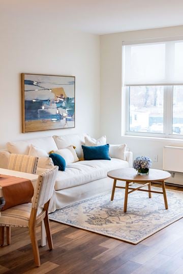 Wyandanch apartment for rent - A living room with a white couch, a brown chair, and a painting on the wall.