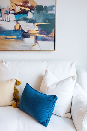 Wyandanch apartment for rent - A painting hangs on a wall above a white couch with pillows.