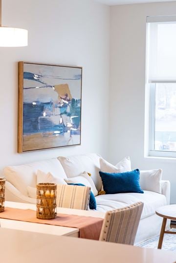 Wyandanch apartment for rent - A living room with a white couch and a painting on the wall.