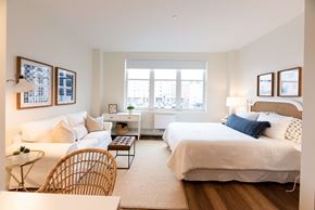 Wyandanch apartment for rent - A bedroom with a large bed and a window overlooking a cityscape.