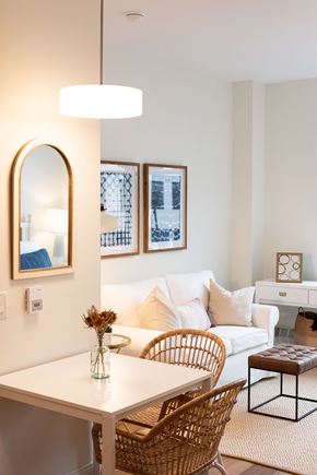 Wyandanch apartment for rent - A white dining table with a wicker chair and a brown leather ottoman.