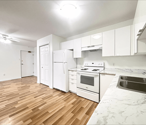 Moncton apartment for rent - A kitchen with white appliances and wooden floors.