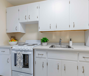 Fredericton apartment for rent - A white kitchen with a stove, sink, and cabinets.