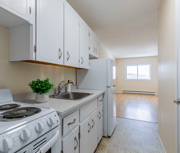 Fredericton apartment for rent - A kitchen with white cabinets and a stove top oven.