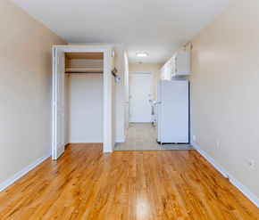 Fredericton apartment for rent - A room with a white fridge and wooden floors.