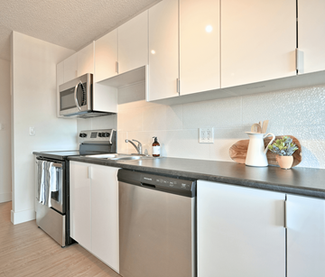 Fredericton apartment for rent - A modern kitchen with white cabinets and stainless steel appliances.