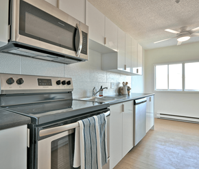 Fredericton apartment for rent - A modern kitchen with a stove top oven and microwave above it.