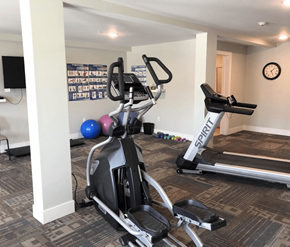 Fredericton apartment for rent - A gym with a treadmill, exercise bike, and weights.