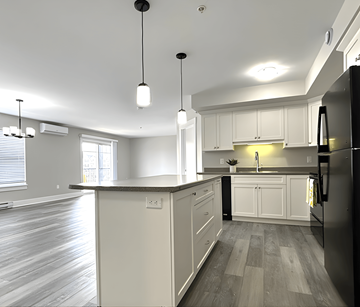 Dieppe apartment for rent - A kitchen with a black refrigerator and white cabinets.