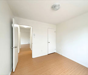 Dieppe apartment for rent - A room with white walls and wooden flooring with a door on the left and a window on the right.