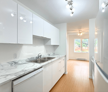 Dieppe apartment for rent - A kitchen with white cabinets and marble countertops.