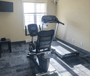 Fredericton apartment for rent - A treadmill and a stationary bike are in a room with a window.