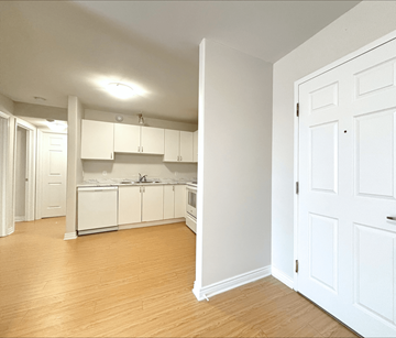 Dieppe apartment for rent - A kitchen with white cabinets and a wooden floor.