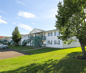 Dieppe apartment for rent - A white building with green railings and a tree in front.