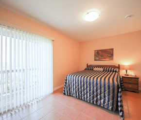 Saint John apartment for rent - A bedroom with a bed, nightstand, and window with blinds.