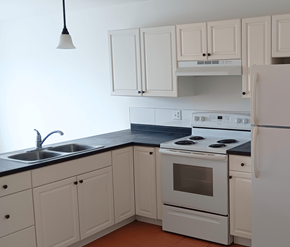 Saint John apartment for rent - A white kitchen with a black counter top and white appliances.