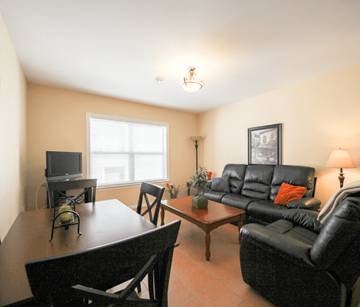 Saint John apartment for rent - A living room with a black leather couch and a wooden coffee table.