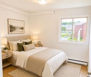 St. Johns apartment for rent - A bedroom with a large bed and a window overlooking a parking lot.