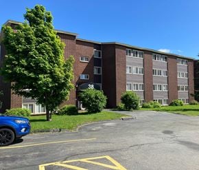St. Johns apartment for rent - A blue car is parked in a parking lot in front of a brick building.