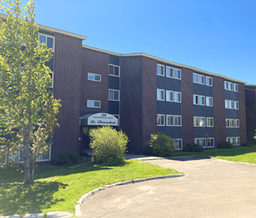 St. John's apartment for rent - A brick building with a sign that says "Pinecrest Le Banquet" in front of it.