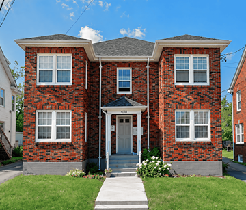 Moncton apartment for rent - A red brick house with a grey roof and a white door.